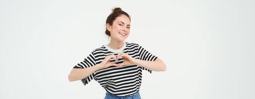 retrato de hermosa niña muestra corazón firmar, amor gesto, me gusta algo, soportes terminado blanco antecedentes foto