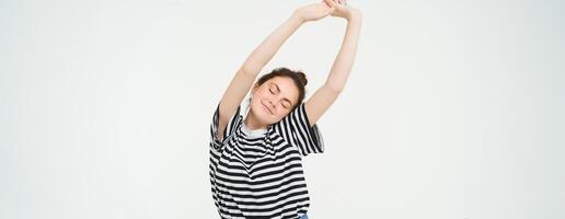 Image of beautiful girl stretching her arms with pleased, satisfied face expression, isolated against white background photo