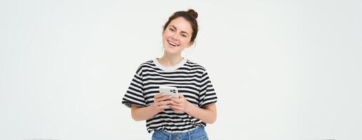 Image of young smiling woman, holding mobile phone, using smartphone application, isolated over white background photo