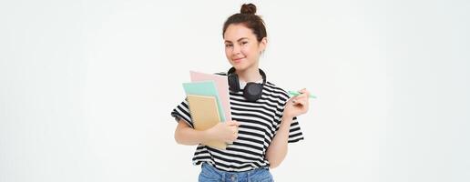 retrato de joven mujer, estudiante con cuadernos y auriculares en su cuello, posando para Universidad anuncio publicitario, blanco antecedentes foto