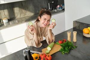Portrait of good-looking woman cooking salad in the kitchen, chopping vegetables and smiling, preparing healthy meal, leading healthy lifestyle and eating raw food photo