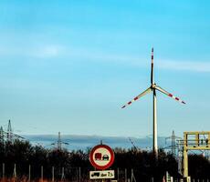 Wind farm park and high voltage towers next to a road in Austria in sunny weather. photo