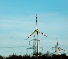 viento granja parque y alto voltaje torres siguiente a un la carretera en Austria en soleado clima. foto