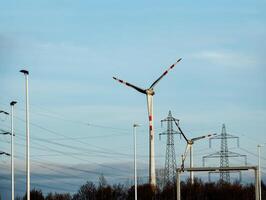 Wind farm park and high voltage towers next to a road in Austria in sunny weather. photo