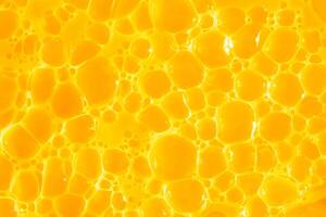 Orange juice. Bubble yellow texture background. Berry gel to cleanse the skin of the face and body. Spa treatments, skin care. Bath foam, detergent. Gold slime photo