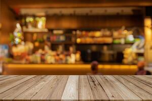 image of wooden table in front of abstract blurred background of coffee shop lights.Blur coffee shop or cafe restaurant with abstract bokeh light background. photo