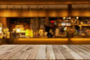 image of wooden table in front of abstract blurred background of coffee shop lights.Blur coffee shop or cafe restaurant with abstract bokeh light background. photo