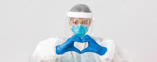 Covid-19, coronavirus disease, healthcare workers concept. Close-up of confident and caring asian female doctor in personal protective equipment, showing heart gesture to patients photo