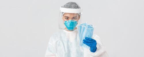 Covid-19, coronavirus disease, healthcare workers concept. Confident serious-looking female asian doctor in personal protective equipment insist patient wearing medical masks, white background photo