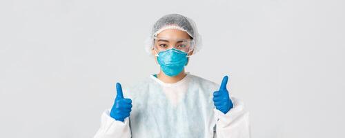 Covid-19, coronavirus disease, healthcare workers concept. Close-up of confident professional female asian doctor, tech lab employee in personal protective equipment show thumbs-up in approval photo