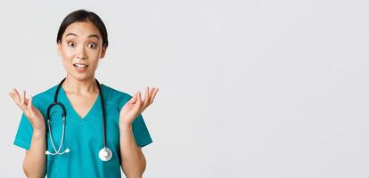 Healthcare workers, preventing virus, quarantine campaign concept. Close-up of surprised and amused, happy asian female nurse, physician hear great news, raise hands amazed and look camera photo