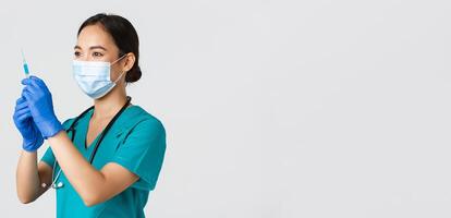 Covid-19, coronavirus disease, healthcare workers concept. Side view of confident smiling asian female physician, nurse prepare syringe with vaccine for flu shot, standing white background photo