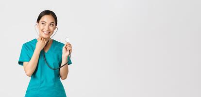 Covid-19, healthcare workers and preventing virus concept. Smiling cute asian doctor, female nurse examine patient lungs, using stethoscope, listening closer, standing white background photo