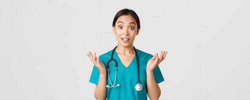 Healthcare workers, preventing virus, quarantine campaign concept. Close-up of surprised and amused, happy asian female nurse, physician hear great news, raise hands amazed and look camera photo