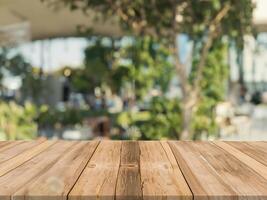 de madera tablero vacío mesa parte superior en de borroso antecedentes. perspectiva marrón madera mesa terminado difuminar en café tienda antecedentes - lata ser usado burlarse de arriba para montaje productos monitor o diseño llave visual disposición. foto