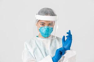 Covid-19, coronavirus disease, healthcare workers concept. Close-up of confident, professional female doctor put on personal protective equipment and rubber gloves to examine patient photo