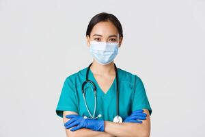 Covid-19, coronavirus disease, healthcare workers concept. Close-up of confident smiling, professional asian doctor, nurse in medical mask and rubber gloves ready for examination, white background photo