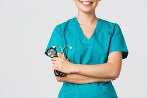 Covid-19, coronavirus disease, healthcare workers concept. Cropped shot of asian female doctor body smiling, cross arms chest confident and holding stethoscope, standing white background photo