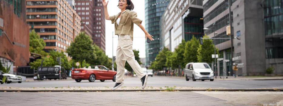 retrato de asiático contento niña saltando y bailando en ciudad centro, posando en calles, Rápido alegría y emoción foto