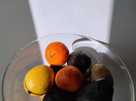 Tropical fruits in a glass vase. Lemon, avocado, tangerine and other photo