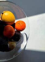 Tropical fruits in a glass vase. Lemon, avocado, tangerine and other photo