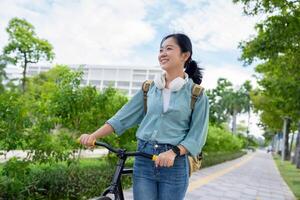 Happy Asian woman taking a walk with a bicycle in the park, copy space photo