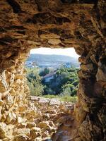 View through the window of an ancient stone tower onto a natural landscape. photo