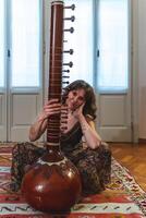 woman sitting on the floor is playing Indian sitar photo