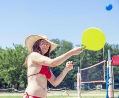 Young adult woman playing tennis on the beach photo