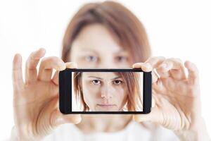 bonito mujer tomando un selfie utilizando su teléfono inteligente foto