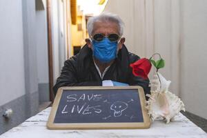 adult man with mask sitting at a table is showing a positive message photo