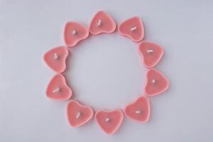 Small pink candles in the shape of a heart are placed in a round frame. A place for your text. photo