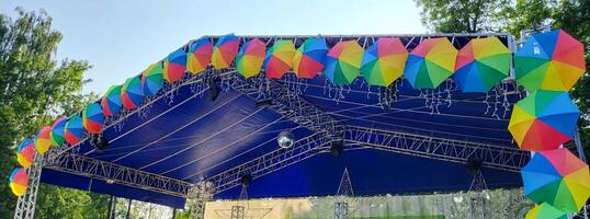 The blue roof of the summer stage in the children's park is decorated with colorful umbrellas. photo