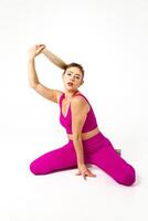 Woman in vibrant pink sports outfit both knees on floor, one hand on floor, other holding hairs up in air photo