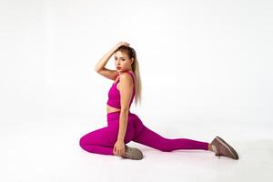 Woman in vibrant pink sports outfit on floor with one hand extended and other bent photo