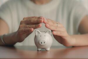 Woman hands covering piggy bank and saving money photo