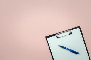 Clipboard and pen with empty pages for writing and sketching on pink background photo