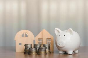 Piggy bank with coins and the wooden house model for business, finance, saving money and property investment concept photo