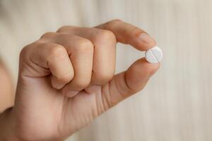 Close up of a female hand holding a pill photo