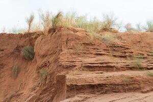 Sand quarry with layers of clay and sand and grass, material extraction. Copy space photo