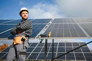 Professional worker installing solar panels on the metal construction, using different equipment, wearing helmet. Innovative solution for energy solving. Use renewable resources. Green energy. photo