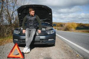 hombre con roto coche en el medio de el la carretera. foto