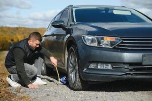 Man with broken down car flat tire in the middle of the street photo