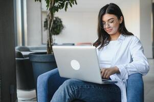 Beautiful Caucasian woman dreaming about something while sitting with portable net-book in modern cafe bar, young charming female freelancer thinking about new ideas during work on laptop computer photo