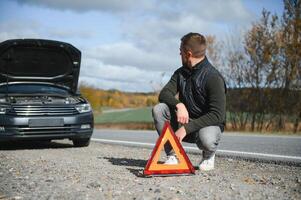 A young man with a black car that broke down on the road,copy space. photo