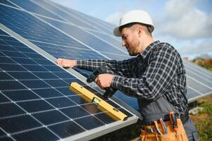 Male worker in uniform outdoors with solar batteries at sunny day. photo