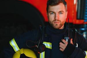 Firefighter portrait on duty. Photo fireman with gas mask and helmet near fire engine.