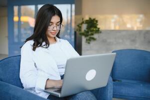 Smiling girl student study online with skype teacher, happy young woman learn language listen lecture watch webinar write notes look at laptop sit in cafe, distant education photo