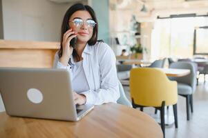 Beautiful Caucasian woman dreaming about something while sitting with portable net-book in modern cafe bar, young charming female freelancer thinking about new ideas during work on laptop computer photo