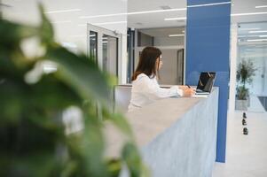 simpático joven mujer detrás el recepción escritorio administrador foto